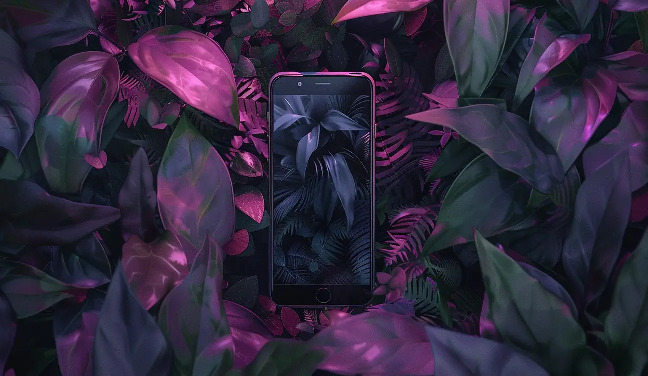 Mobile phone sitting up amongst tropical plants.